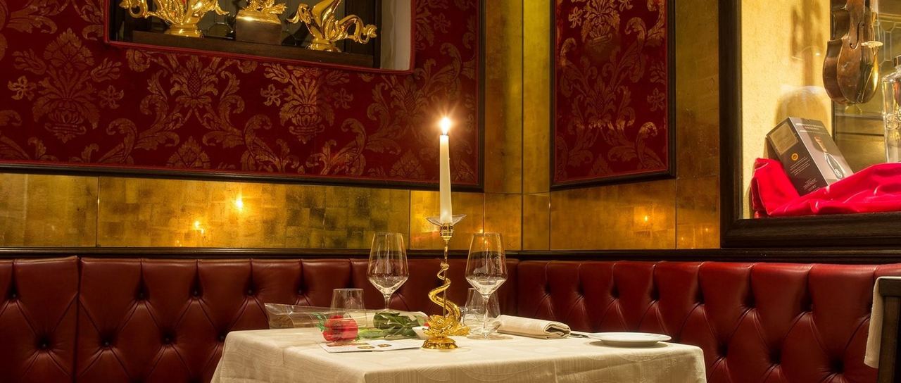 A candlelit table at Bistrot de Venise, against red damask and gilded walls