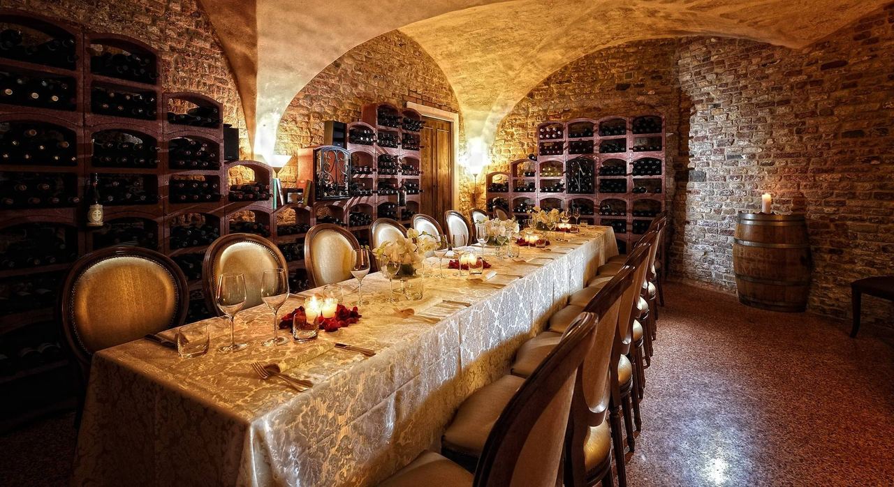 A long candlelit table in the vaulted wine cellar of Alle Corone