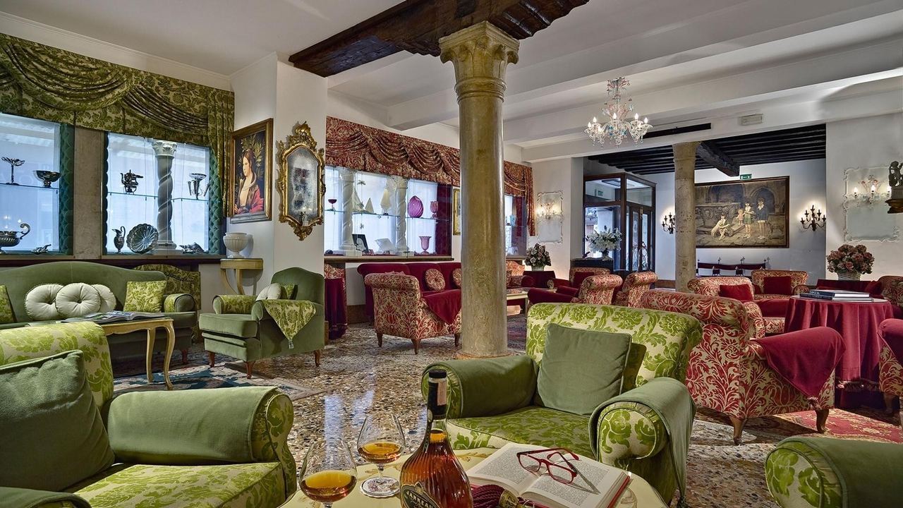 The lounge of Hotel Giorgione, with damask armchairs, a stone column and terrazzo floor
