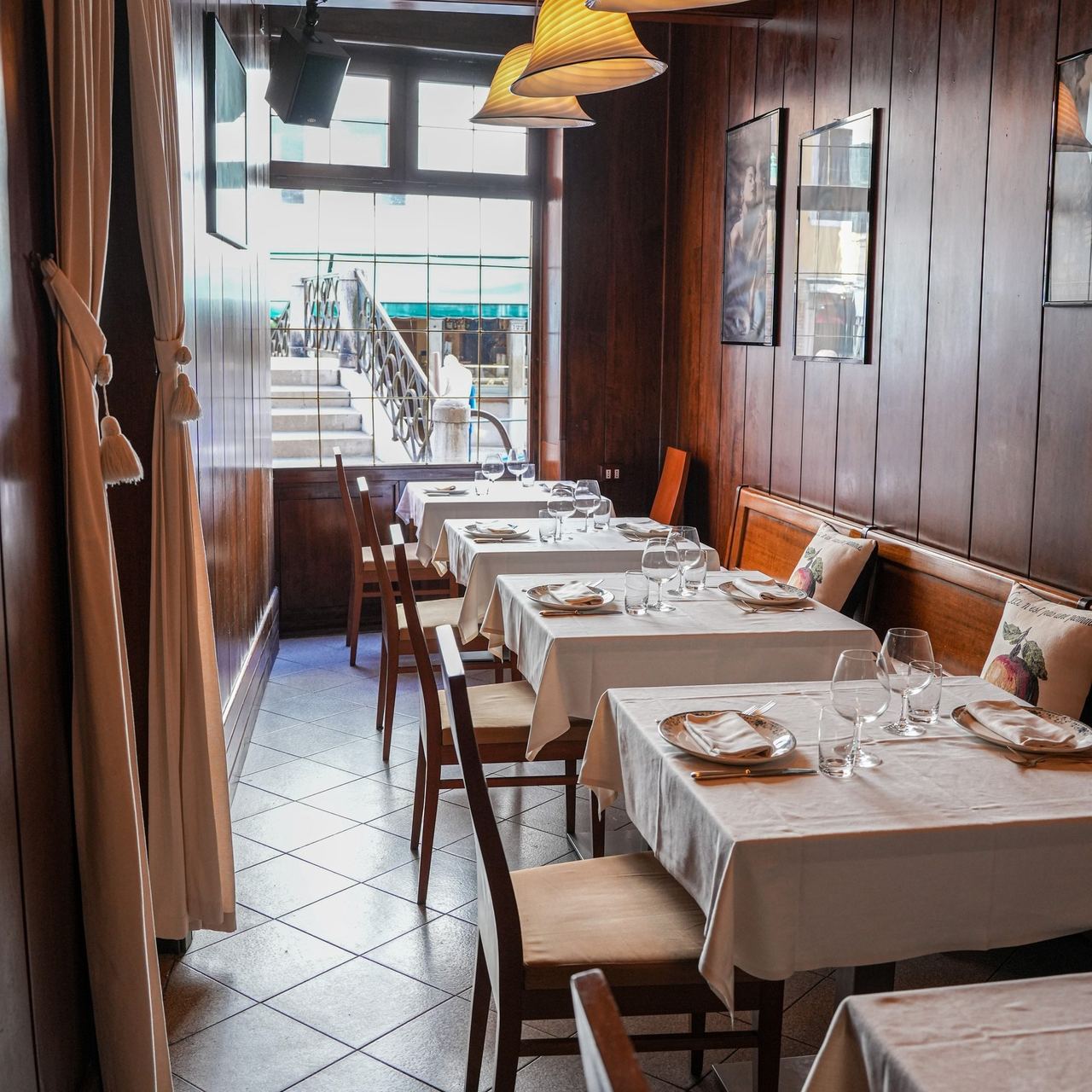The wood-panelled dining room of Ai Gondolieri, with tables laid along the window