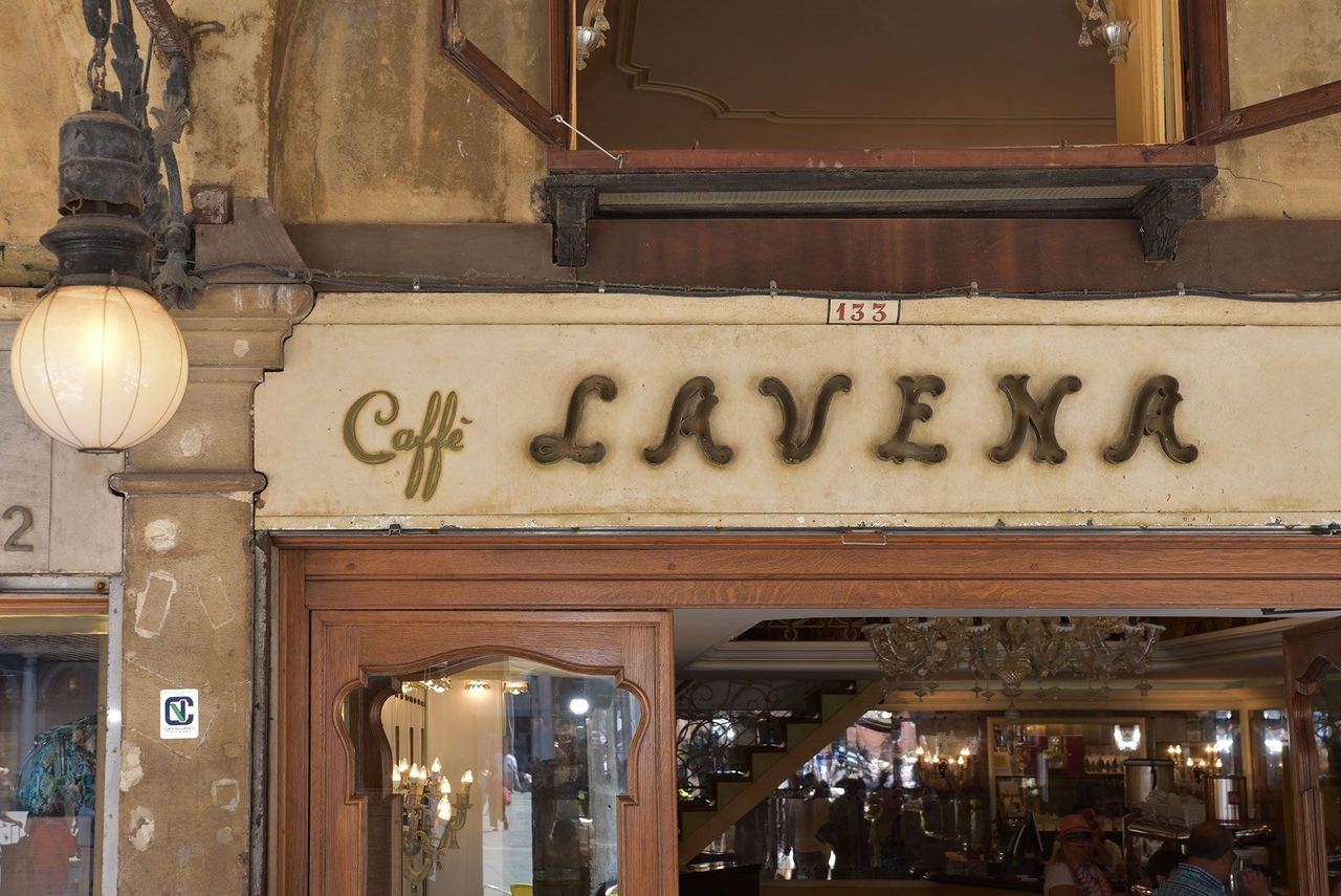 The old gilt lettering of Caffè Lavena above its door under the Procuratie