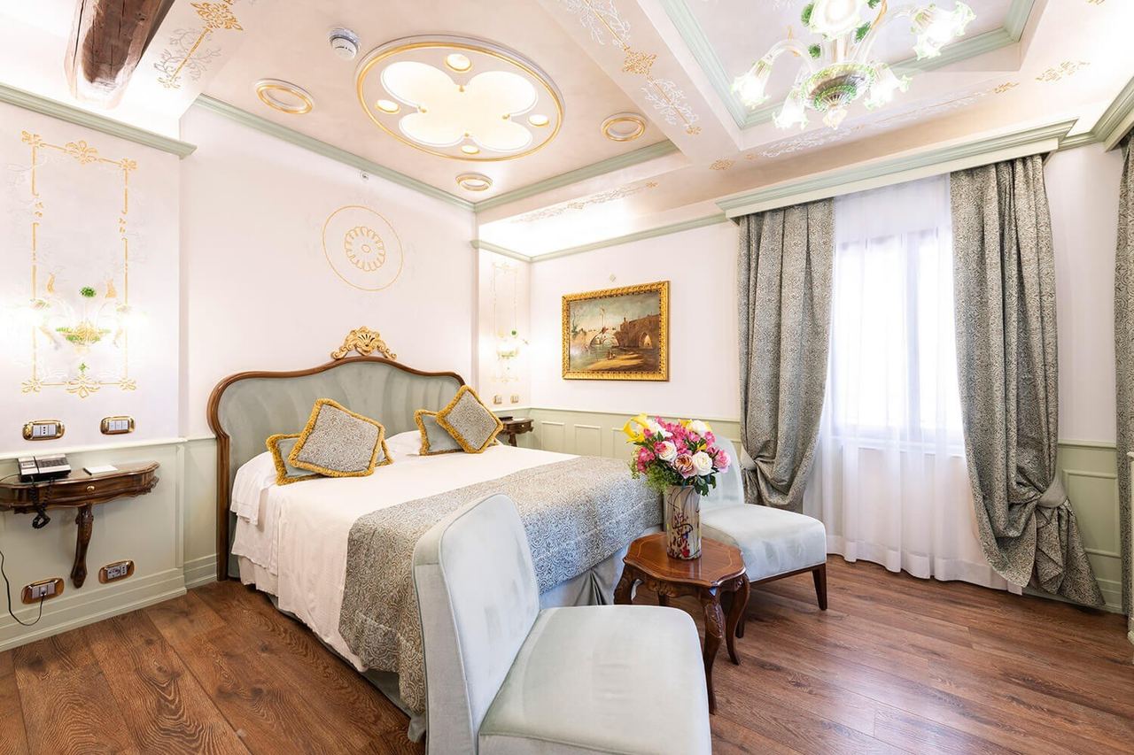 A bedroom at Hotel Monaco & Grand Canal, with a Murano chandelier and painted plasterwork