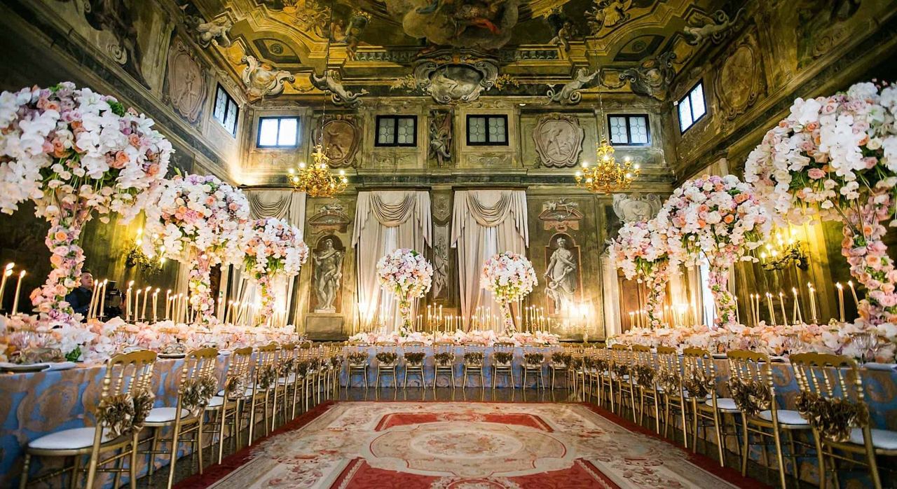 The frescoed ballroom of Ca’ Sagredo laid for a banquet among candles and flowers