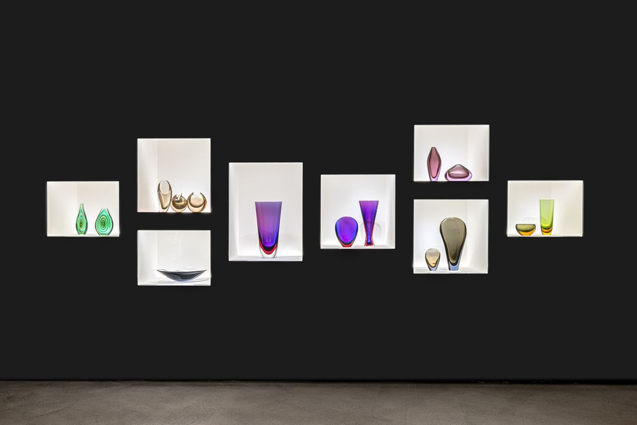 Coloured glass vases lit in white niches at Le Stanze del Vetro